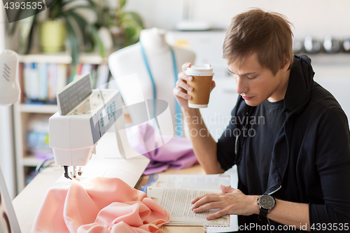 Image of fashion designer with coffee and book at studio