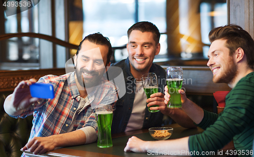 Image of friends taking selfie with green beer at pub