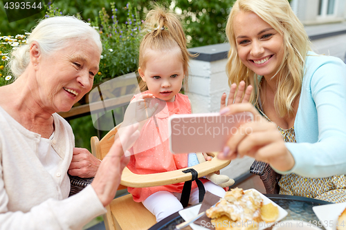 Image of happy family taking selfie at cafe