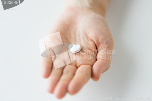 Image of close up of hand holding medicine heart pill