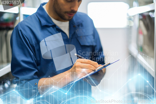 Image of auto mechanic with clipboard at car workshop