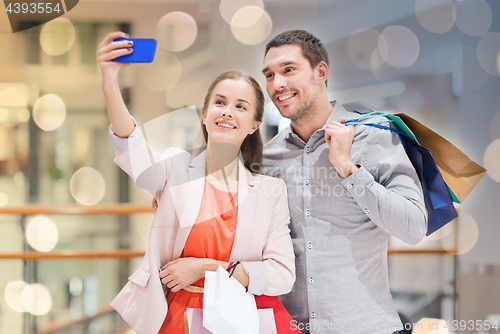 Image of happy couple with smartphone taking selfie in mall