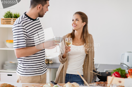 Image of couple cooking food and drinking wine at home