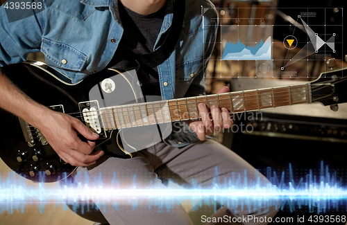 Image of close up of musician playing guitar at studio