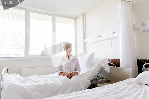 Image of sad senior woman sitting on bed at hospital ward