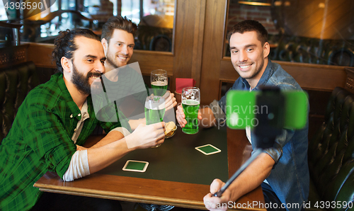 Image of friends taking selfie with green beer at pub