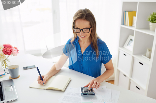 Image of woman with calculator and notebook at office