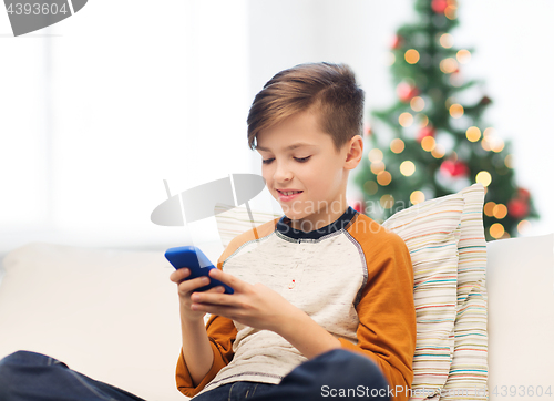 Image of boy playing on smartphone at home at christmas