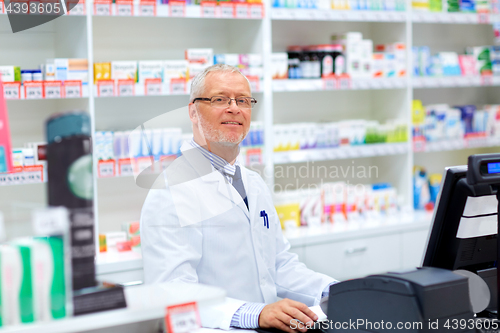 Image of senior apothecary at pharmacy cash register