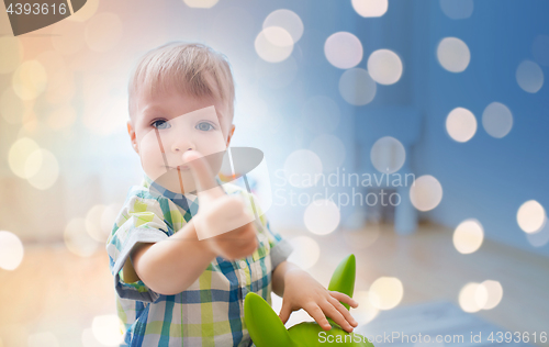 Image of happy baby boy playing with toy showing thumbs up