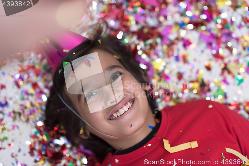 Image of kid blowing confetti while lying on the floor