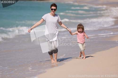 Image of mother and daughter running on the beach