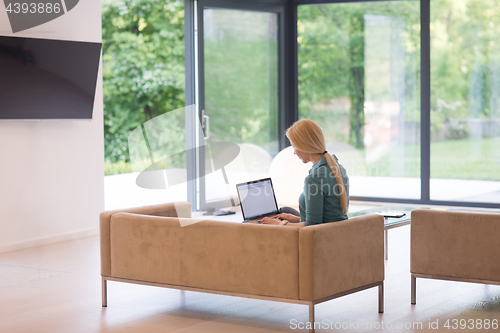 Image of Young woman using laptop at home