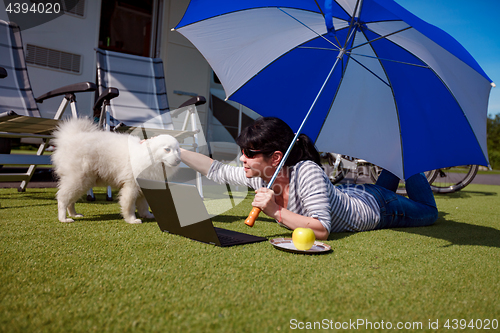 Image of Woman on the grass with a dog looking at a laptop