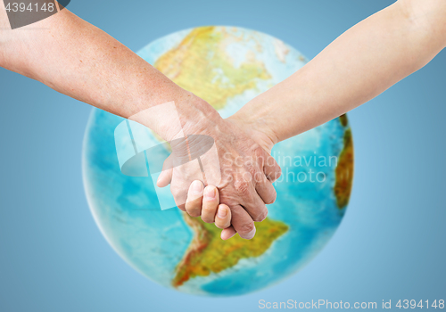 Image of close up of senior and young woman holding hands