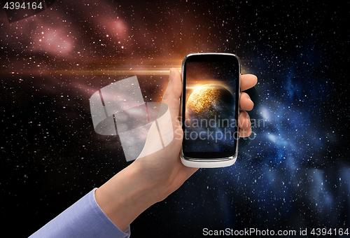 Image of hand with planet on smartphone screen over space