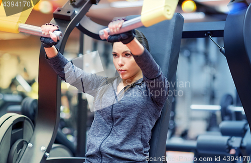 Image of woman flexing muscles on chest press gym machine 