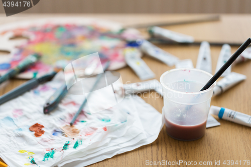 Image of paintbrush soaking in cup of water on table
