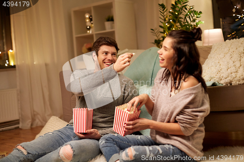 Image of happy couple eating popcorn at home