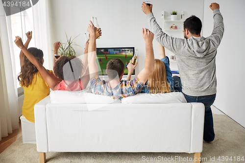 Image of friends with beer watching soccer on tv at home