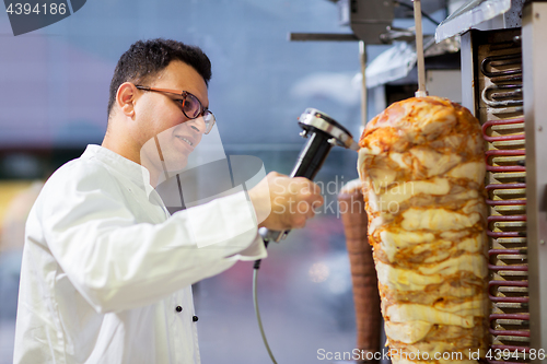 Image of chef slicing doner meat from spit at kebab shop