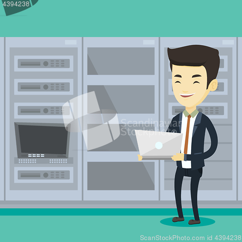 Image of Engineer working on laptop in network server room.