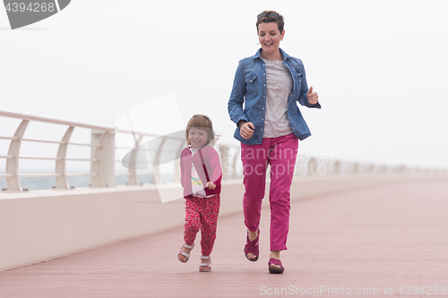 Image of mother and cute little girl on the promenade by the sea