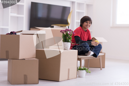 Image of boy sitting on the table with cardboard boxes around him