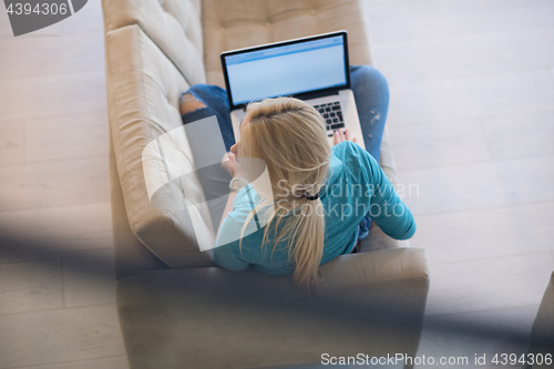 Image of Young woman using laptop at home