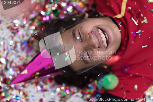 Image of kid blowing confetti while lying on the floor