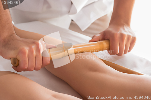 Image of Detail of hands massaging human calf muscle.