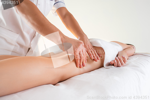 Image of Detail of hands massaging human calf muscle.