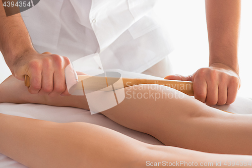 Image of Detail of hands massaging human calf muscle.