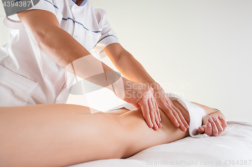 Image of Detail of hands massaging human calf muscle.