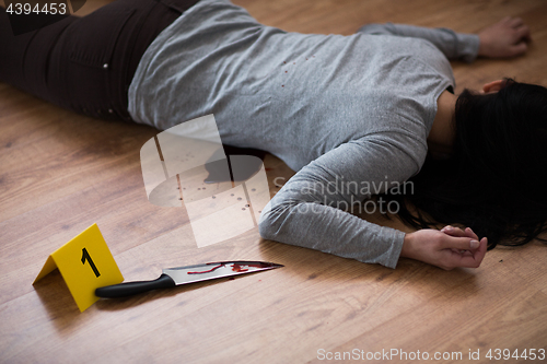 Image of dead woman body lying on floor at crime scene