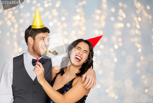 Image of happy couple with party blowers having fun