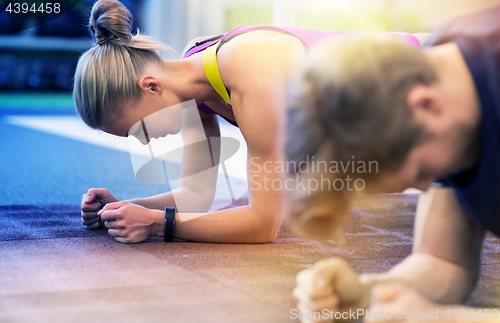 Image of woman and man doing plank exercise in gym