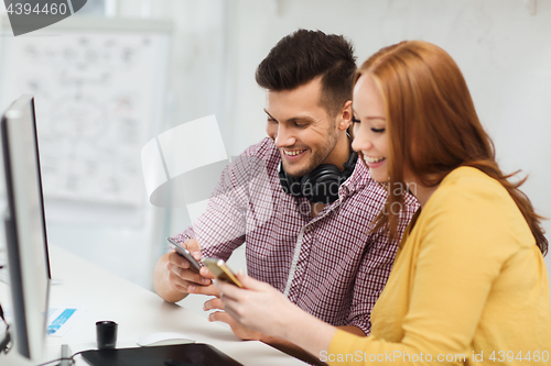 Image of smiling creative team with smartphones at office