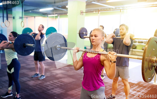 Image of group of people training with barbells in gym