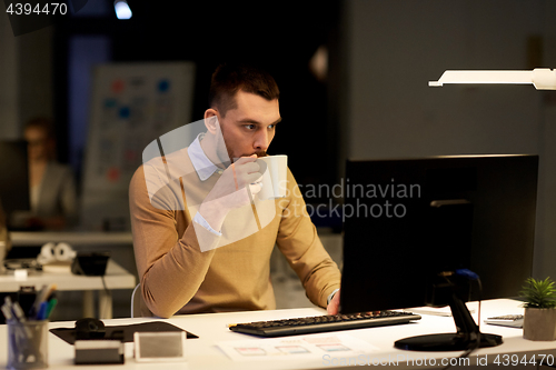 Image of man with laptop and coffee working at night office