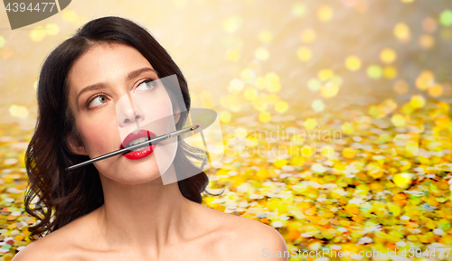 Image of beautiful woman holding make up brush for lipstick