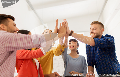 Image of happy creative team making high five at office