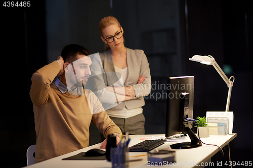 Image of business team with computer working late at office