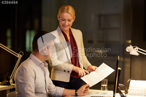 Image of business team with papers working late at office