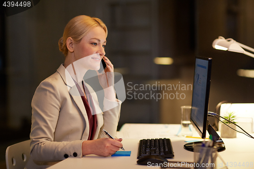 Image of businesswoman calling on sartphone at night office