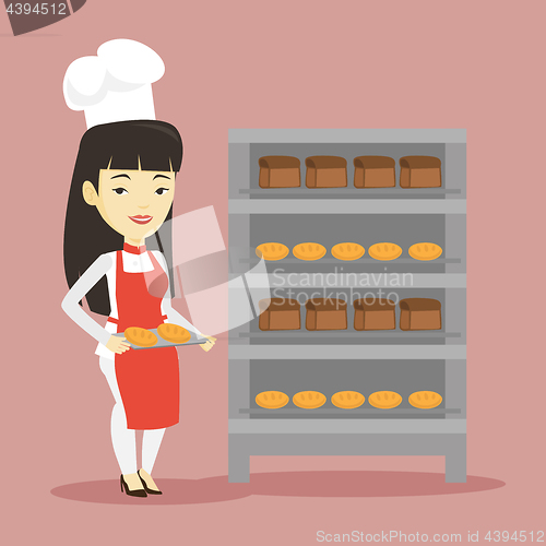 Image of Happy young female baker holding tray of bread.