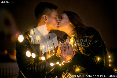 Image of Young couple kissing and hugging outdoor in night street at chri