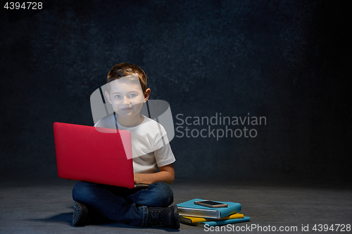 Image of Little boy sitting with laptop in studio