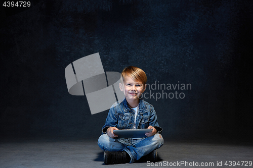 Image of Little boy sitting with tablet in studio