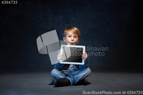 Image of Little boy sitting with tablet in studio